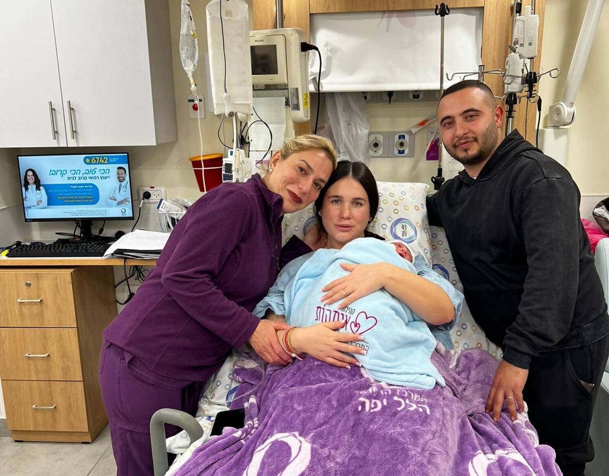 בני הזוג חובקים צאצא טרי עם המיילדת תיקי חן בחדר הלידה ב"הלל יפה"