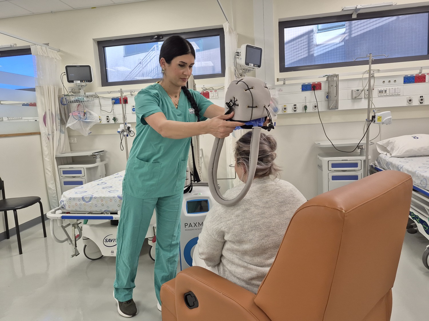 אחות מתאמת שד נאגם ביאדסי מהמכון האונקולוגי בהלל יפה מדריכה מטופלת לשימוש בכובע קרח